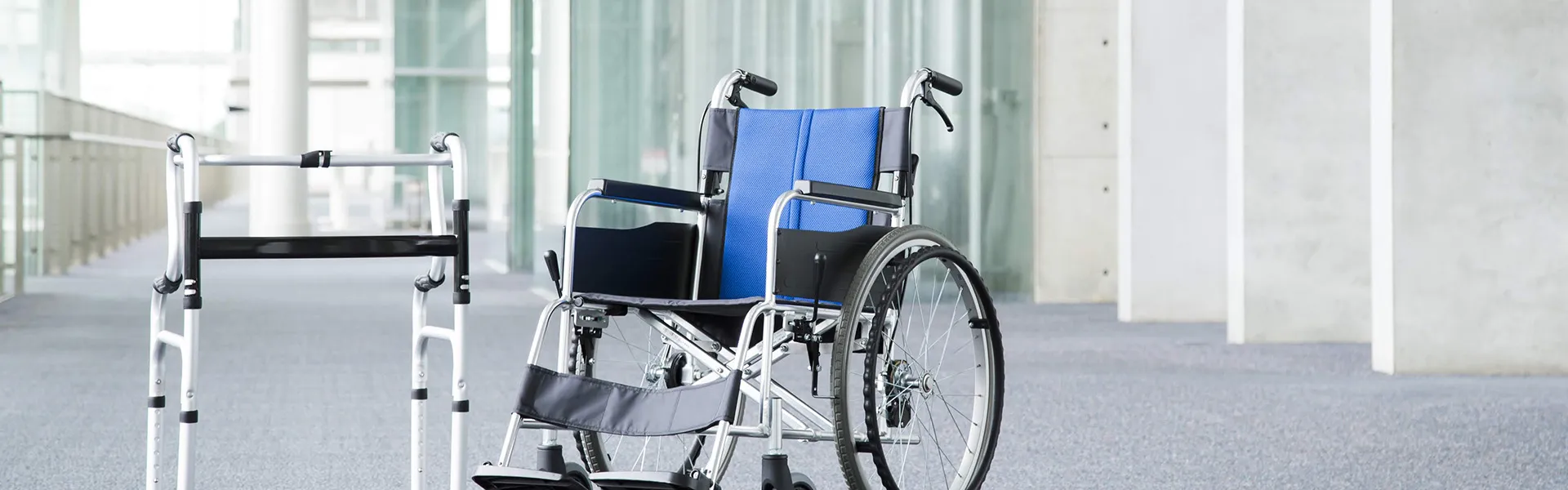介護施設の廊下に置かれた歩行器と車椅子などの福祉機器。